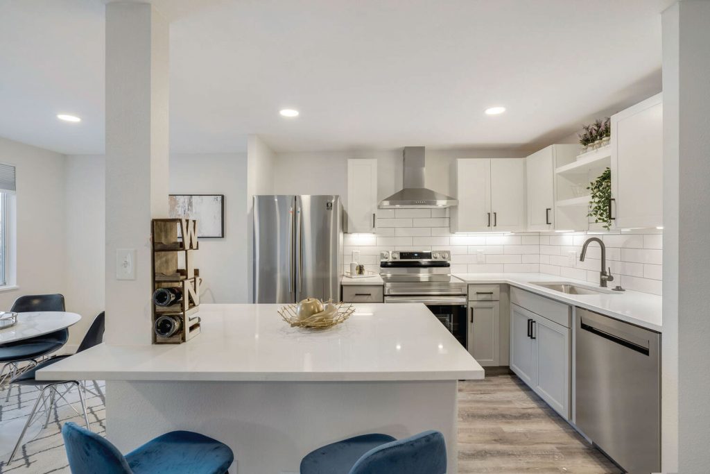 A renovated Iris Apartment Kitchen with stainless steel appliances and a white counter top.